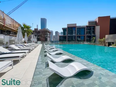 a swimming pool with white lounge chairs next to a building at Luxury One Bedroom with Burj Khalifa View in Dubai