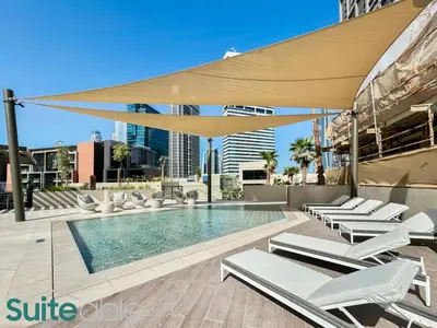 a swimming pool with chairs and a large umbrella at Luxury One Bedroom with Burj Khalifa View in Dubai