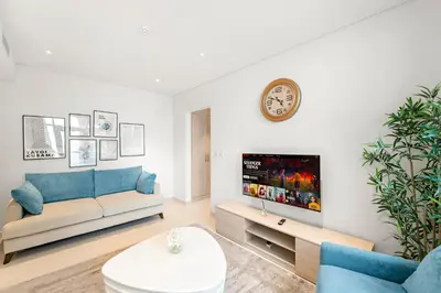 a living room with a couch and a clock on a wall at Luxury 1BR in Seven Palm with Beach Access in Dubai