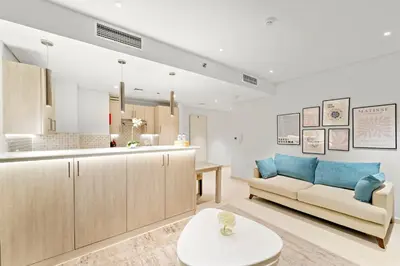 a living room with a couch and a kitchen at Luxury 1BR in Seven Palm with Beach Access in Dubai