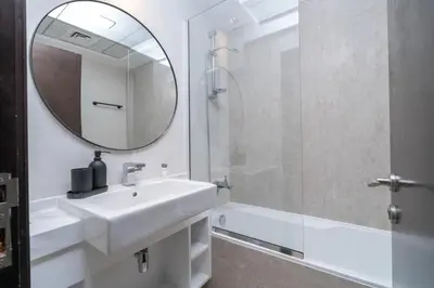 a bathroom with a sink and a mirror and a tub at SUNRISE HOMES - A Modern Studio near JBR Beach in Dubai