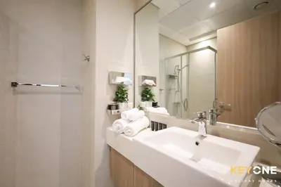 a white bathroom with a sink and a mirror at Exquisite Living in Riviera One Bedroom in Dubai