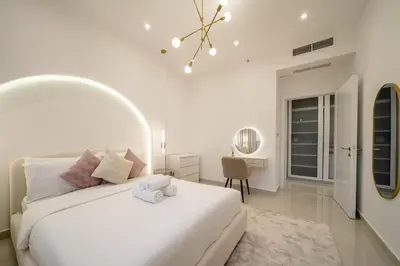 a white bedroom with a white bed and a desk at Lux 5BR Marina Apt with Jacuzzi, Walk to Beach, Gym in Dubai
