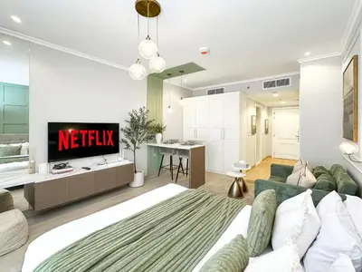 a living room with a couch and a tv at Trophy - Earthy Retreat Studio in JVC in Dubai