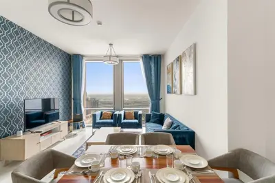 a living room with a table and a blue couch at 2BR Canal View Flat with Pool, Gym, 10 min Drive to Dubai Mall in Dubai
