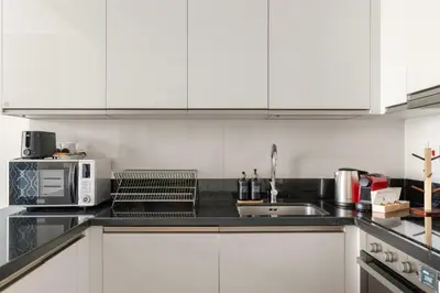 a kitchen with white cabinets and a microwave at 2BR Canal View Flat with Pool, Gym, 10 min Drive to Dubai Mall in Dubai