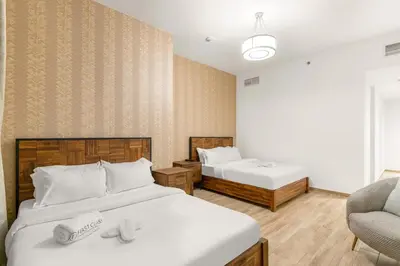 a bedroom with two beds and a chair at 2BR Canal View Flat with Pool, Gym, 10 min Drive to Dubai Mall in Dubai