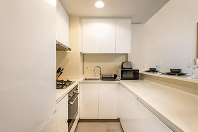 a white kitchen with white cabinets and a sink at Stylish 1BR Business Bay - Near Metro - Balcony with City Views in Dubai