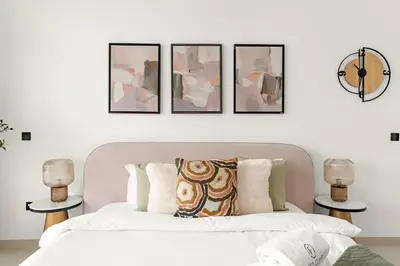 a bedroom with a white bed with four pictures on the wall at Chic Dubai Studio with Balcony, Pool, Gym, Free Parking Near Expo Metro in Dubai