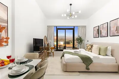 a living room with a bed and a dining room at Chic Dubai Studio with Balcony, Pool, Gym, Free Parking Near Expo Metro in Dubai
