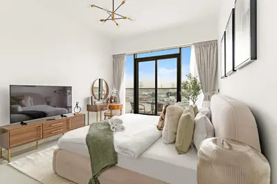 a white bedroom with a bed and a large window at Chic Dubai Studio with Balcony, Pool, Gym, Free Parking Near Expo Metro in Dubai