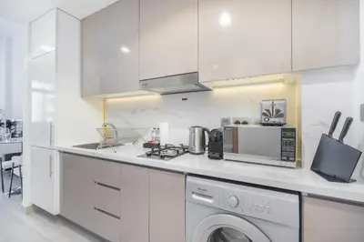 a kitchen with white cabinets and a washer at Dubai Studio - Trendy Interiors - City Views in Dubai