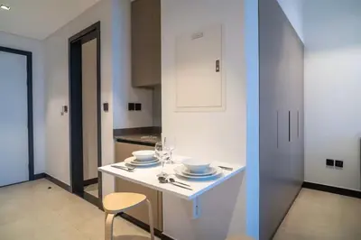 a white kitchen with a table and a chair at Lavish Studio at 15 Northside W City Skyline View 3rd floor in Dubai