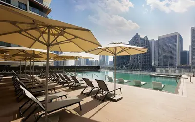 a pool with chairs and umbrellas on a building at Lavish Studio at 15 Northside W City Skyline View 3rd floor in Dubai