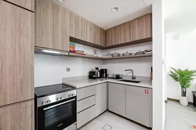 a kitchen with white counters and wooden cabinets at Convenient 1BR apartment in Business Bay in Dubai