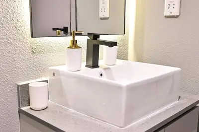a white bathroom sink with two cups on a counter at Charming Studio in Meydan by Deleguest in Dubai