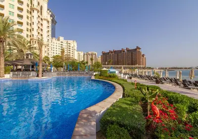 a large swimming pool in a resort with buildings at Bespoke Holiday Homes - 2BR Apartment with Riva Beach Club Access, Al Nabat in Dubai