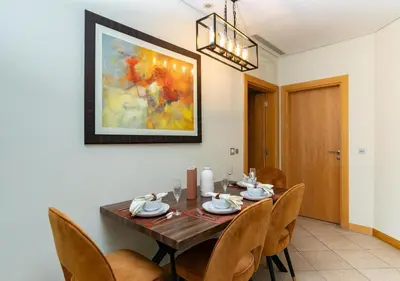 a dining room with a wooden table and chairs at Bespoke Holiday Homes - 2BR Apartment with Riva Beach Club Access, Al Nabat in Dubai