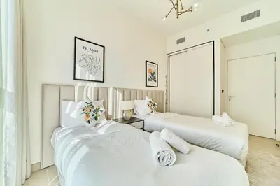 two beds in a room with white walls at Stylish 2BR Apartment Steps from Dubai Hills Mall in Dubai