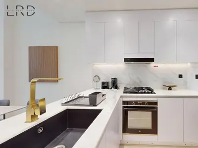 a white kitchen with a sink and a stove at Brand New and Modern Smart Home 1BR in Dubai