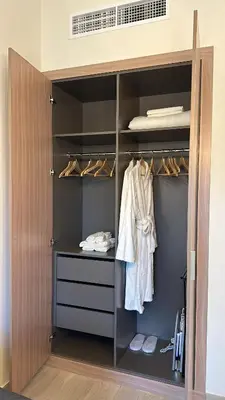 a closet with a wooden door with clothes at Azizi Riviera 44 in Dubai