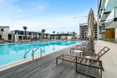a swimming pool with lounge chairs and an umbrella at Lovely 1BR flat wBalcony Gym & Pool in JVC in Dubai