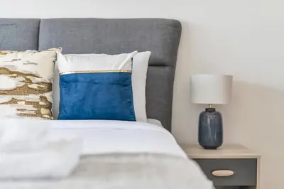 a bed with a blue and white pillow and a lamp at Lovely 1BR flat wBalcony Gym & Pool in JVC in Dubai