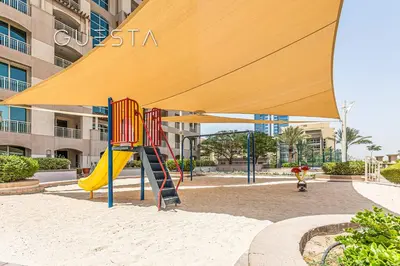 a playground with a yellow umbrella and a slide at The Views & Greens - Mosela Tower, Dubai in Dubai