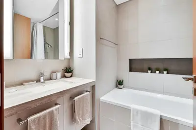 a white bathroom with a sink and a mirror at Stylish 1BR with Pool, Gym, BBQ Area & Playground in Dubai