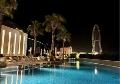 a swimming pool with chairs and palm trees at night at Address Residences Stay in Dubai