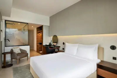 a bedroom with a large white bed and a chair at Hotel Local Dubai, Jumeirah Village Triangle, Autograph Collection in Dubai