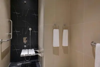 a bathroom with a shower stall with white towels at Hotel Local Dubai, Jumeirah Village Triangle, Autograph Collection in Dubai