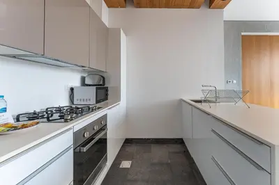 a white kitchen with a stove and a microwave at HAVN - 1 Bed at KOA Canvas, Access to Nasab Dubai in Dubai