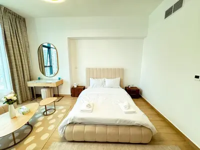 a bedroom with a large bed and a mirror at Modern Studio Living in JVC's Regina Tower in Dubai