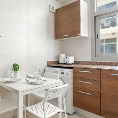 a white kitchen with a white table and chairs at Cozy Studio at DEC Tower in Dubai