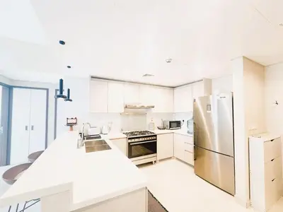 a kitchen with white cabinets and a stainless steel refrigerator at Luxury 1 Bed in the heart of the city! Free WiFi in Dubai