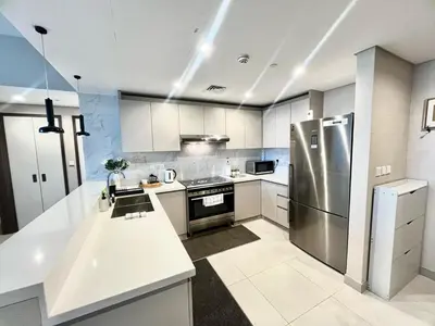 a kitchen with white cabinets and a stainless steel refrigerator at Luxury 1 Bed in the heart of the city! Free WiFi in Dubai