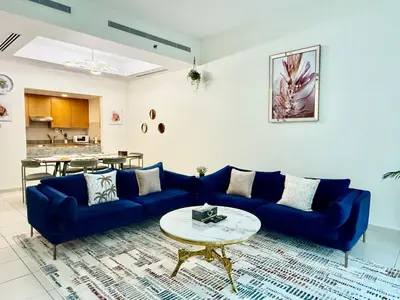 a living room with a blue couch and a table at Nivis find-Affordable & Spacious 1 BHK- 10 Mins to Dubai Mall in Dubai