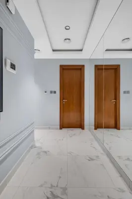a hallway with two wooden doors and marble floors at luxury apartment at Al Habtoor city in Dubai