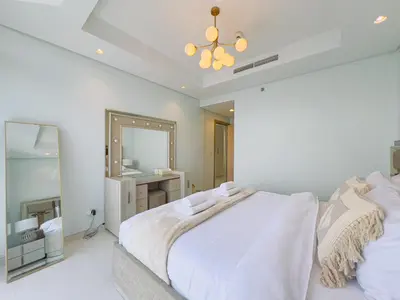 a white bedroom with a large bed and a mirror at Exclusive 1BR with Iconic Views in Paramount Tower in Dubai