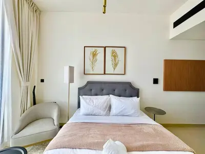 a bedroom with a large bed and a chair at Modern Studio Apt Balcony & Free Parking Jvc in Dubai