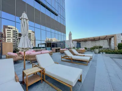 a row of lounge chairs and umbrellas on the roof of a building at High-Rise Studio Overlooking the Sea with a Glimpse of Ain Dubai, The Palm Tower, Palm Jumeirah by Deluxe Holiday Homes in Dubai