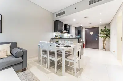 a kitchen and dining room with a white table and chairs at Pool and City View 1BR Near Dubai Water Canal, The Cosmopolitan, Business Bay by Deluxe Holiday Homes in Dubai