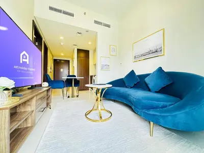 a living room with a blue couch and a tv at AWS Holiday Homes - Top Retreat near the Burj in Dubai