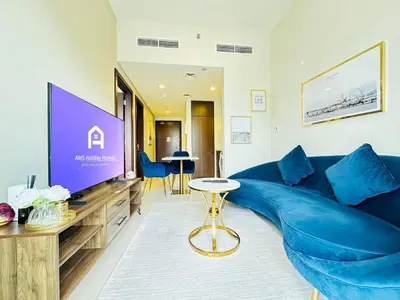 a living room with a blue couch and a tv at AWS Holiday Homes - Top Retreat near the Burj in Dubai