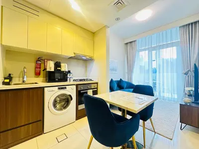 a kitchen with a washing machine and a table and chairs at AWS Holiday Homes - Top Retreat near the Burj in Dubai