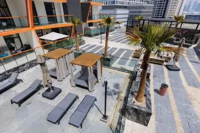 a balcony with tables and palm trees on a building at Contemporary 2 Bedroom Apartment in Dubai
