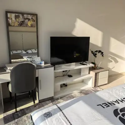 a living room with a television and a desk with a chair at Seven Palm west beach Studio in Dubai