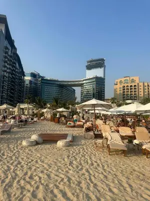a sandy beach with chairs and umbrellas and buildings at Seven Palm west beach Studio in Dubai