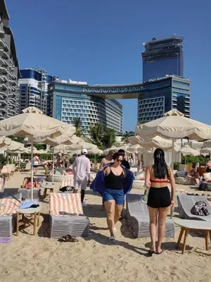 two women walking on a beach with umbrellas at Seven Palm west beach Studio in Dubai